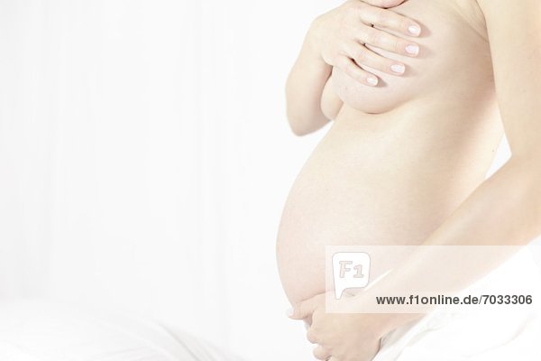 Nackte schwangere Frau berührt ihre Bauch