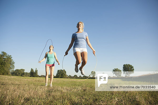 Zwei junge Frauen machen Seilspringen auf einer Wiese