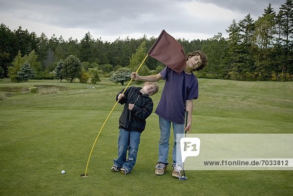 Two Boys Being Playful On A Golf Course