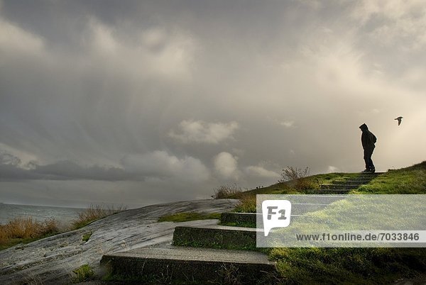 Person Standing On Cliff Overlooking Stormy Sea