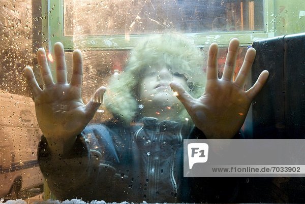 Child With Hands Pressed Against Winter Window