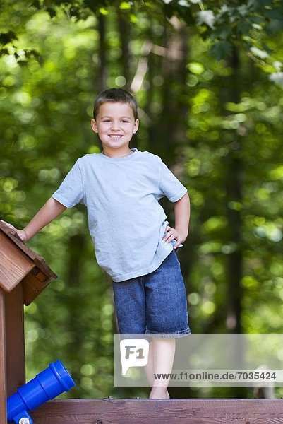 Young Boy Standing On Top Of Jungle Gym Smiling