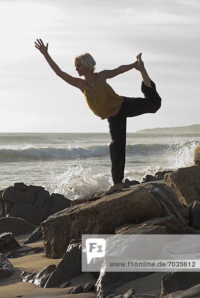 Mature Woman In Yoga Position On Shoreline