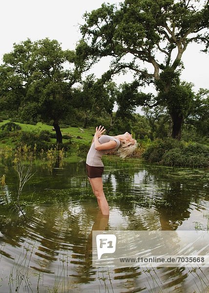 Mature Woman In Yoga Position In Lake