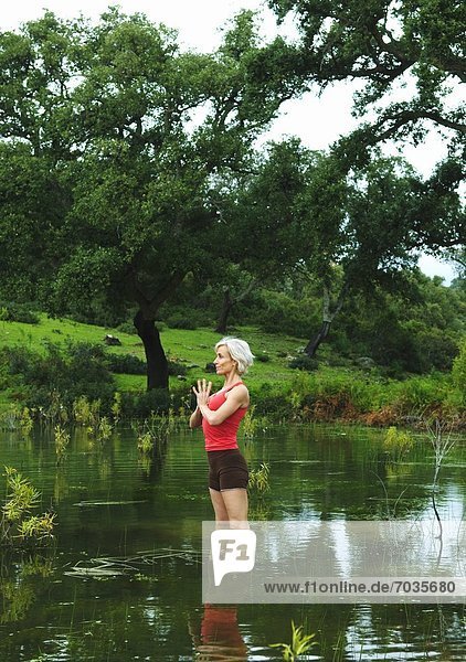 Mature Woman In Yoga Position In Lake