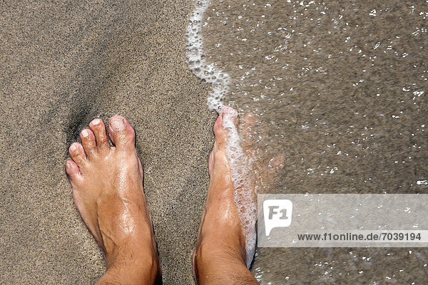 Feet on a beach  being lapped by the sea