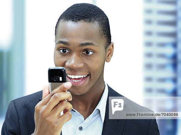 Happy young businessman  African-American  American  looking at his mobile phone  checking texts  surprised