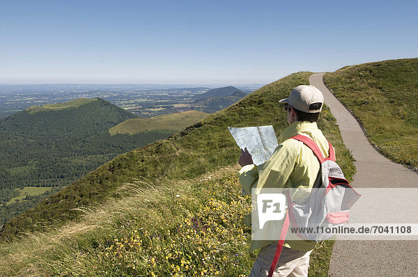 Wanderer mit Aussicht vom Puy de Dome auf die Vulkanlandschaft der Chaine des Puys  Auvergne  Frankreich  Europa