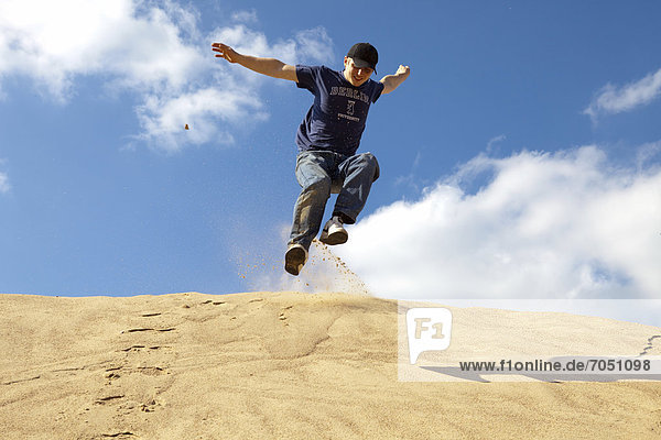 Ein junger Mann springt einen Sandhügel hinunter  Öttingen  Bayern  Deutschland  Europa