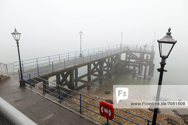Portsmouth pier / jetty with street lamps and life preserver in fog