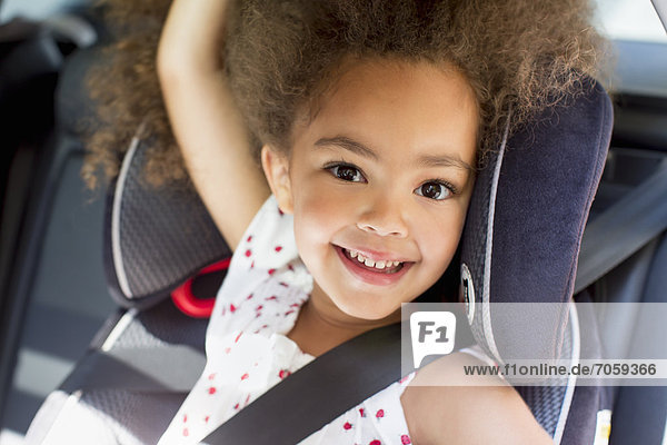 Mixed race girl sitting in car seat