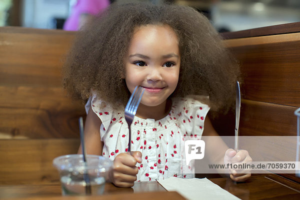 Mixed race girl waiting for food in restaurant