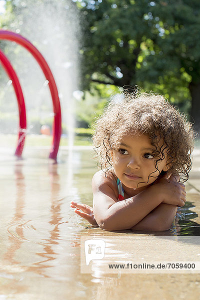 Mixed race girl playing in fountain