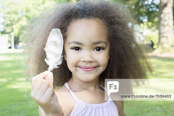 Mixed race girl holding a feather