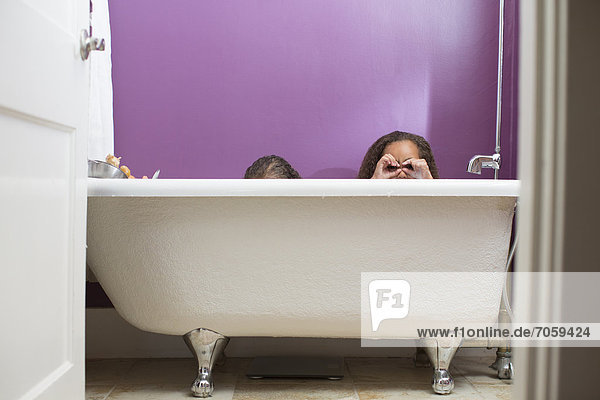 Mixed race girls playing in bathtub