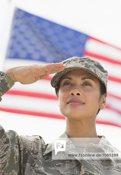 Female army soldier saluting  American flag in background