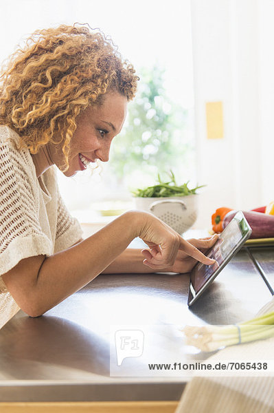 Young woman using digital tablet in kitchen