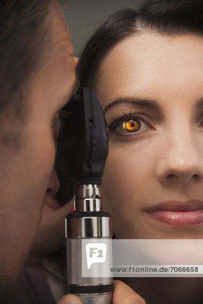 Close up of woman's eye lit up from doctor doing eye test