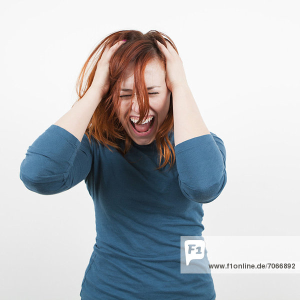 Studio shot  Portrait of woman holding her head and screaming
