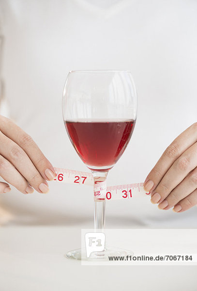 Woman measuring glass with rose wine