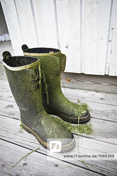 Schmutzige Gummistiefel auf Holzdiele