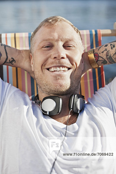 Porträt eines Mannes mit Kopfhörer zum Entspannen am Strand