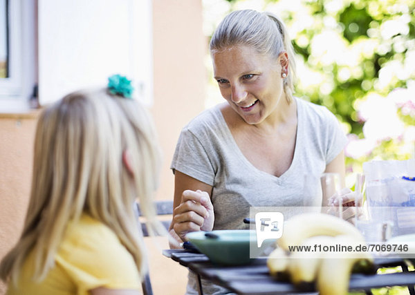 Glückliche Frau mit Tochter am Frühstückstisch
