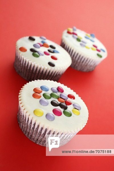 White cupcakes decorated with coloured chocolate beans