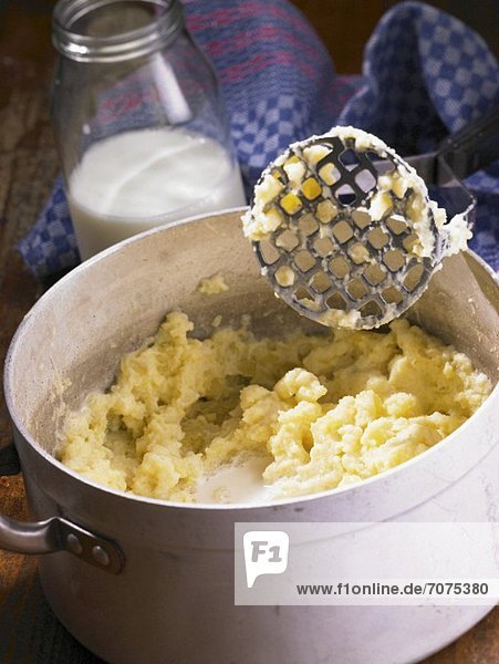 Mashed potatoes and a masher in a pot