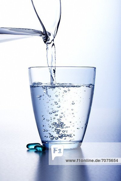 Wasser aus Krug in ein Glas giessen