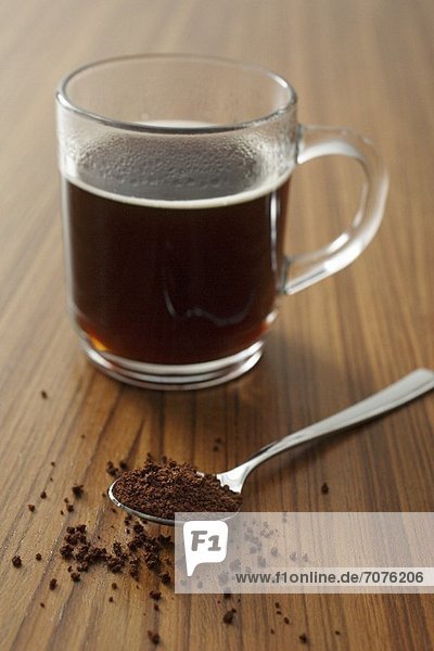 A cup of instant coffee and a spoonful of instant coffee powder