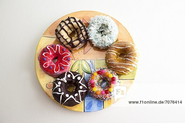 Gebackene Doughnuts mit verschiedenen Toppings auf einem bunten Teller