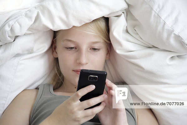 liegend liegen liegt liegendes liegender liegende daliegen Bett Mädchen Smartphone