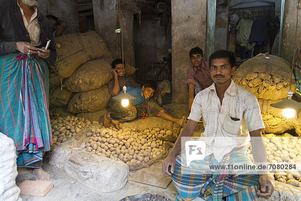 Markthändler sitzen zwischen Kartoffeln und Jutesäcken  Gew¸rzmarkt  Old Dhaka  Dhaka  Bangladesch  S¸dasien