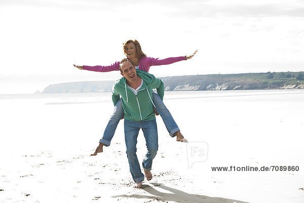 Mann trägt Frau huckepack am Strand  Bretagne  Frankreich  Europa