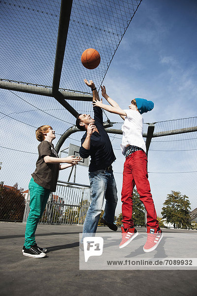 Vater und zwei Söhne spielen Basketball