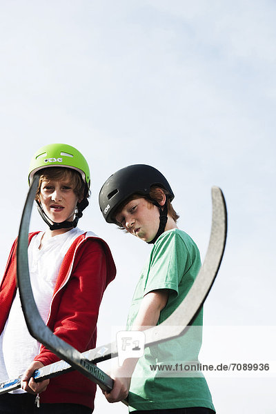 Zwei Jungen posieren mit Hockeyschlägern