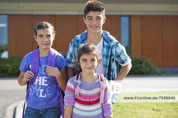 Drei lächelnde Kinder mit Schultaschen