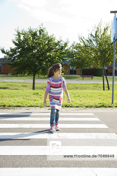 Mädchen überquert die Straße an einem Zebrastreifen auf einem Verkehrsübungsplatz