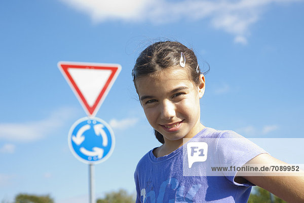 Lächelndes Mädchen steht vor einem Verkehrsschild  Portrait