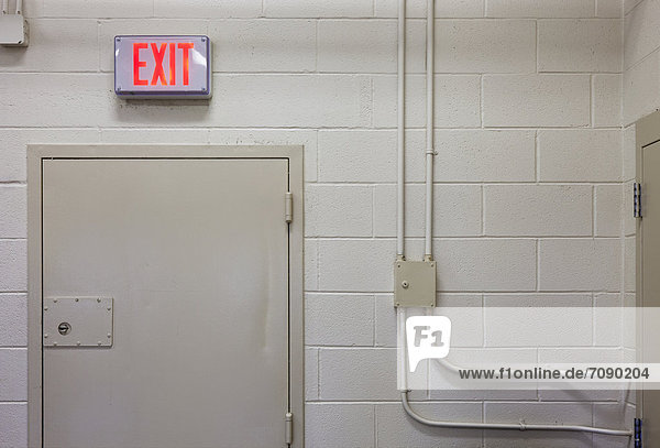 Interior of a prison unit. Exit sign and securely locked door at Correctional Facility.