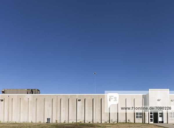 The exterior of a concrete building with no windows at a Correctional Facility.