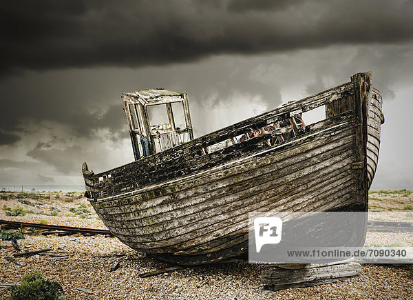 A wooden fishing boat  on the beach at Dungeness. A dark stormy sky.