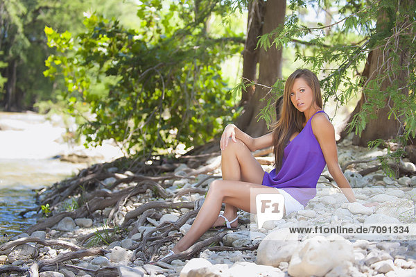 USA  Texas  Young woman sitting at Frio river