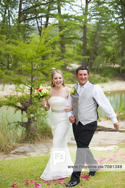 USA  Texas  Bride and groom walking on grass  smiling