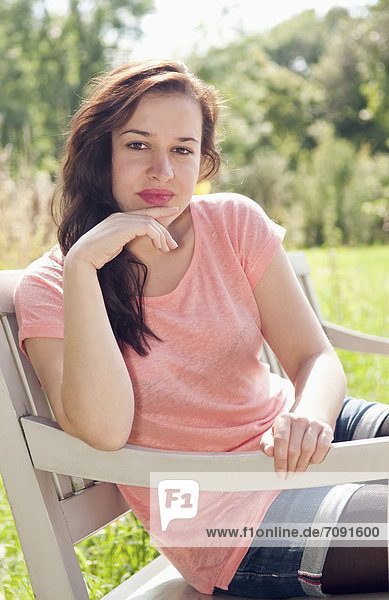 Young woman sitting on park bench  smiling  portrait