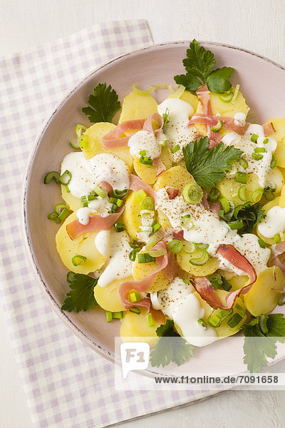 Potato salad garnished with spring onions  parsley and mayonnaise  close up