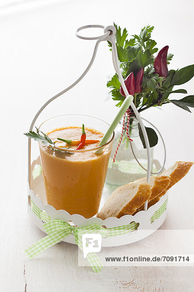 Glass of gazpacho with chillies  bread and parsley on tray