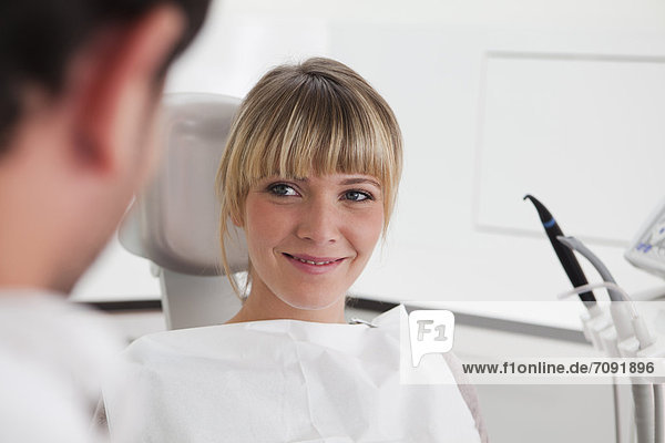 Germany  Young woman in dentist chair  smiling