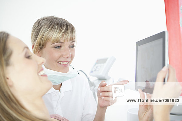 Germany  Dentist and patient with digital tablet in dental office